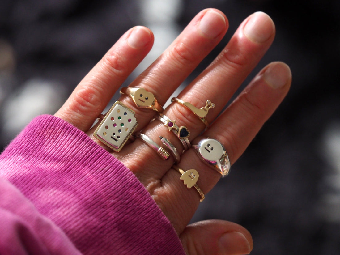 A ladies hand with silver and gold rings being stacked on all fingers